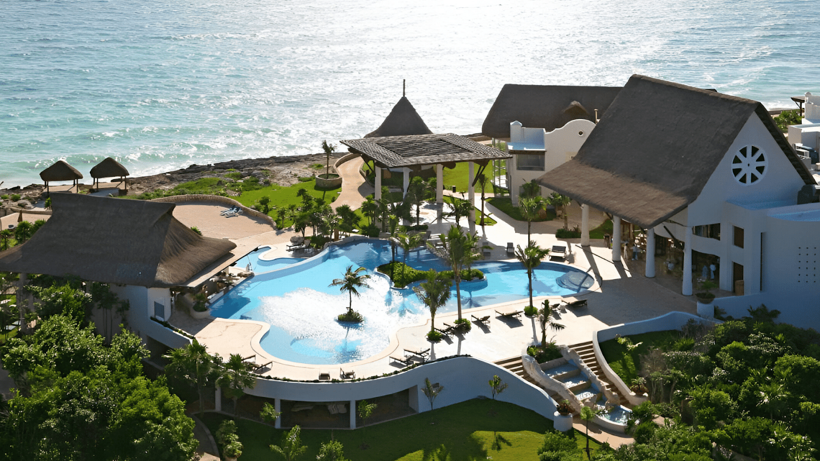 Elevated view of a beachfront resort pool in Tulum, illustrating the secure and relaxing atmosphere for travelers seeking a serene retreat