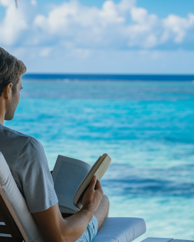A male guest reading a book from his beachfront vacation rental in the Maldives