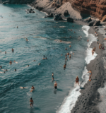 People swimming on the black sand beach of Santorini