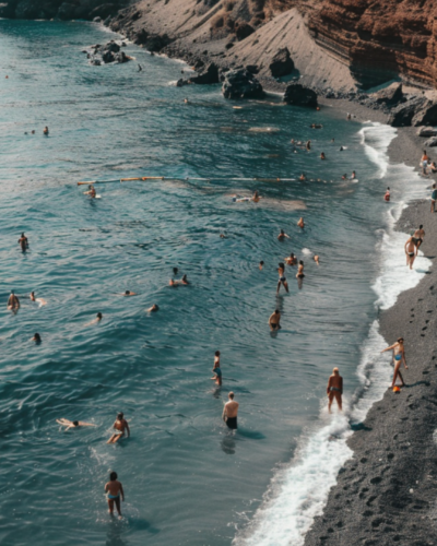 People swimming on the black sand beach of Santorini