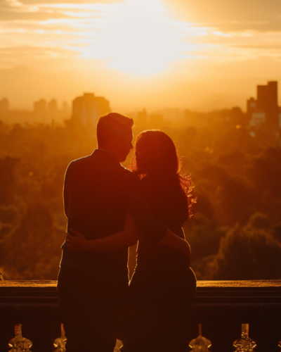 Couple embracing at a scenic overlook as the sun sets over Mexico City skyline