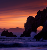 Silhouette of the Arch of Cabo San Lucas against a colorful sunrise sky, Los Cabos, Mexico.