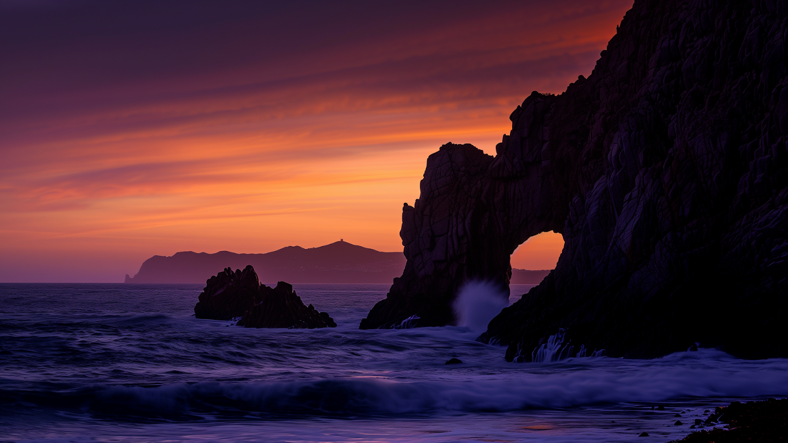 Silhouette of the Arch of Cabo San Lucas against a colorful sunrise sky, Los Cabos, Mexico.